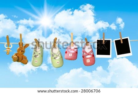 Baby shoes, pacifier and teddy bear on clothesline with blue sky