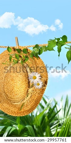 Summer straw hat with daisies on clothesline against blue sky