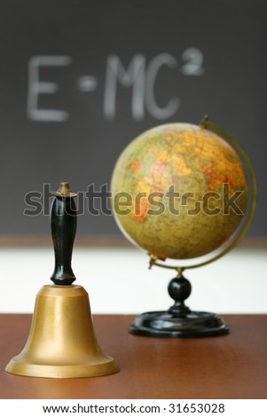 Old school bell on desk in front of chalkboard