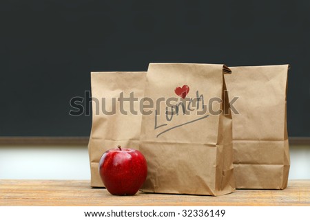 Paper lunch bags with red apple on school desk