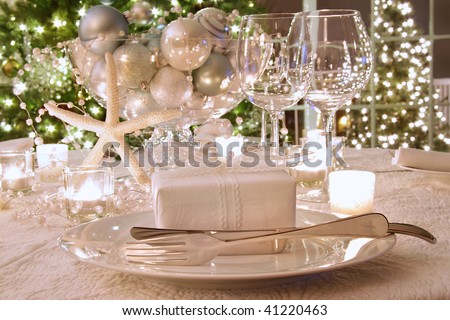 Elegantly lit  holiday dinner table with wine glasses and white ribbon gift