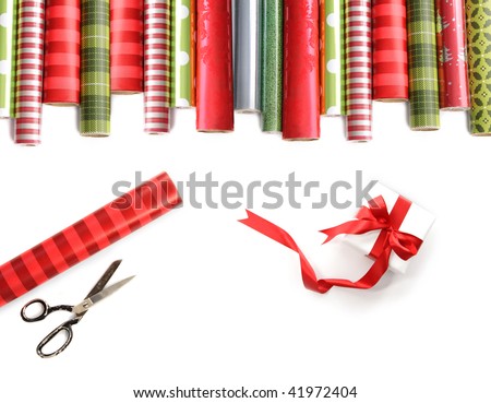 Rolls of colored wrapping  paper with scissors and gift on white background