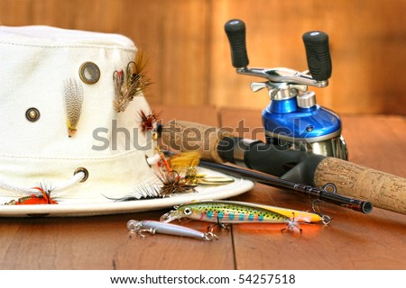 Fishing reel with hat and color lures on wood