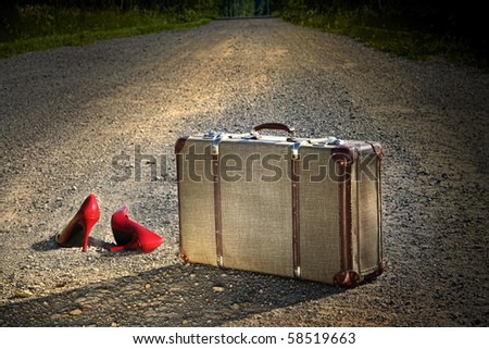 Old suitcase with red shoes left on dirt road