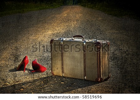 Old suitcase with red shoes left on a dirt road