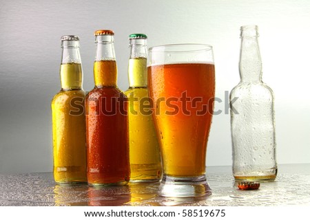 Glass of beer with bottles on stainless counter
