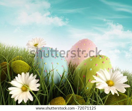 Three decorated easter eggs in the grass with daisies
