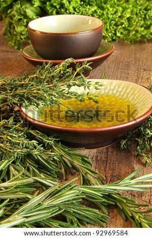 Fresh herbs with olive oil on wooden cutting board