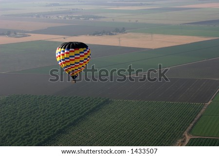 hot air balloon flying over farmlands