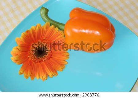 orange bell pepper and daisy on turquoise plate