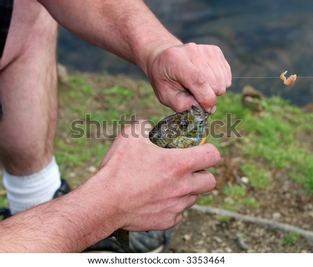 man taking hook out of fish's mouth