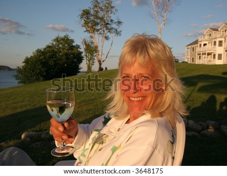 beautiful blond woman sitting in sun with glass of wine