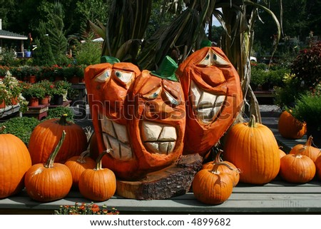 large carved wooden pumpkins and smaller pumpkins and plants