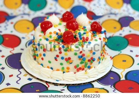 fun colorful cake with cherries on top of festive tablecloth