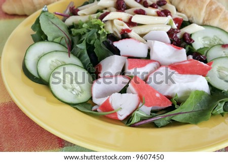 large salad with imitation crab meat,cucumber,pasta,spinach,greens,lettuce,cranberry-raisins