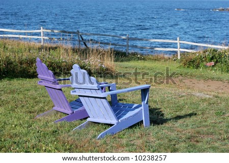 purple and blue adirondack chairs on lawn facing ocean