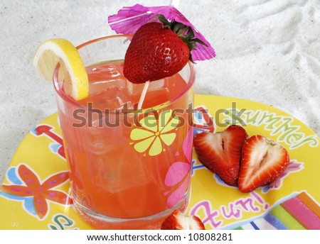 tropical drink with strawberries and lemon on decorative dish in sand