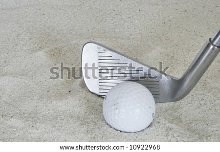 golf club and golf ball in sand trap