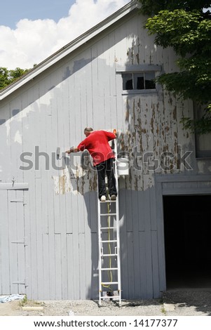 man on ladder painting barn wall