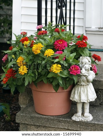 beautiful planter with colorful zinnia flowers with humorous statue of little girl about to kiss a frog