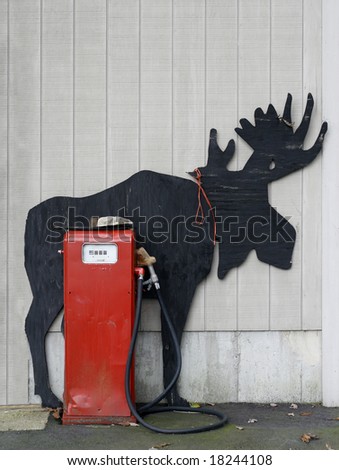 moose cut out against gray wall with red vintage gas pump
