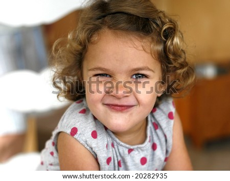 adorable toddler girl with curly hair, scrunching nose