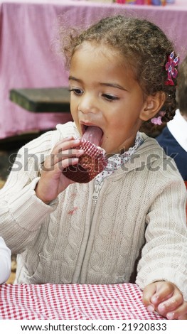 adorable toddler girl eating cupcake