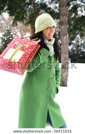 beautiful young woman holding holiday shopping bag in outdoor winter setting