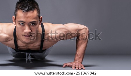 Young asian man workout over grey background