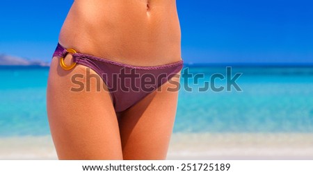 Beautiful woman\'s bikini body on the beach in front of turquoise water - shot in Sardinia