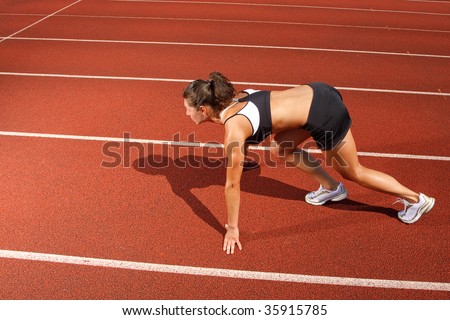 Athletic woman on track starting to run