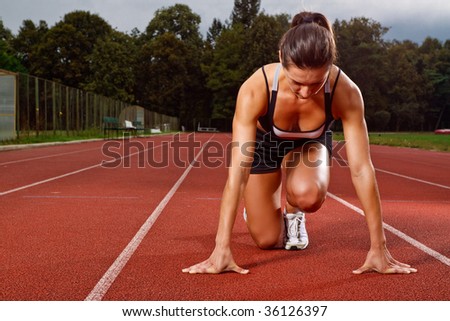 Athletic woman in start position on track