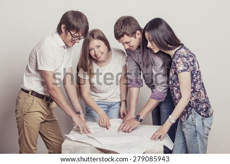 People who work with drawings on the table in the white room