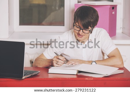 The young man working at home at the table with laptop