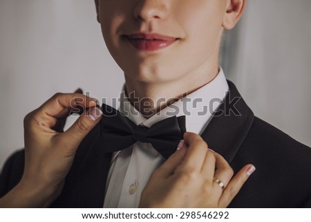 Man the groom in a wedding costume with butterfly smiles. Hands, lips, bride, care, to correct, to adjust, fashion.