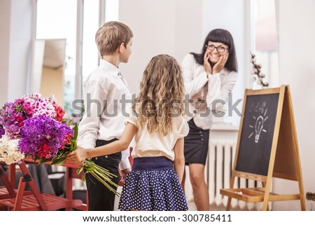 Boy and girl children give flowers as a school teacher in teacher\'s day. The day of knowledge, education, appreciation, generation.