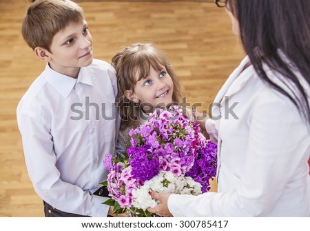 Boy and girl children give flowers as a school teacher in teacher\'s day. The day of knowledge, education, appreciation, generation.