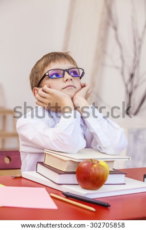 Boy, child, at school, at a school Desk with books in the glasses. Education, intelligence, genius, vision, school, class.