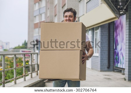Porter, the man with cardboard boxes in the hands of a strong, delivery to the door. Fast delivery, reliability, deliveryman.