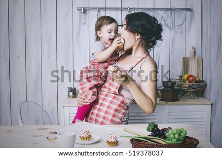 Mother and small child in the kitchen at home beautiful and happy aprons