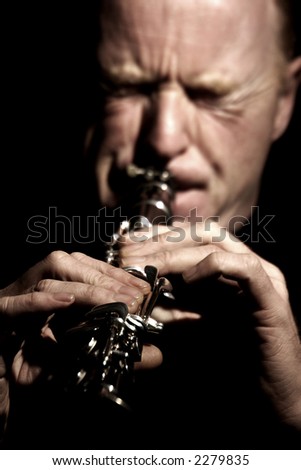 musician playing a clarinet isolated against black background