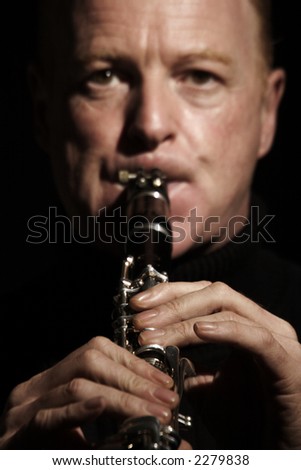 musician playing a clarinet isolated against black background