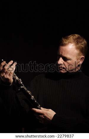 musician holding a clarinet isolated against black background
