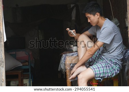 Huaibei, Anhui, China, June 22, 2015. A teenager sitting at home playing mobile games. At present, the mobile phone in China has become the main communication and entertainment tool.