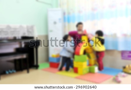 Kindergarten teachers and children in the indoor play building blocks, blurry background.