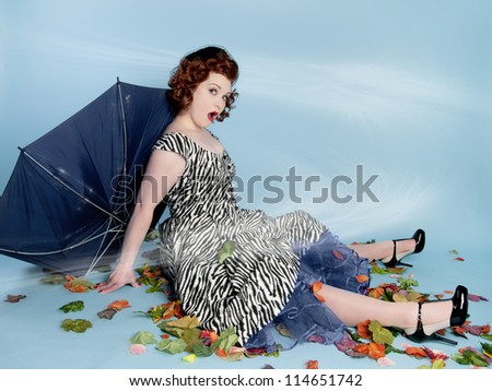 Cute pinup girl holding a broken umbrella in wind