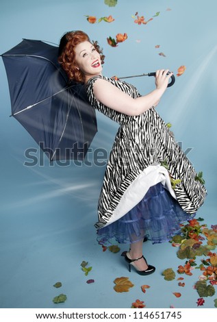 Cute pinup girl holding a broken umbrella in wind