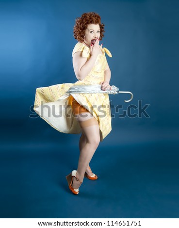 Cute pinup girl holding an umbrella pulling up her dress