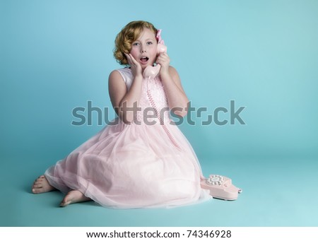 Cute little girl talking on a vintage pink telephone