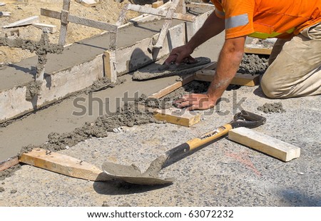 Worker laying concrete curb with spreader